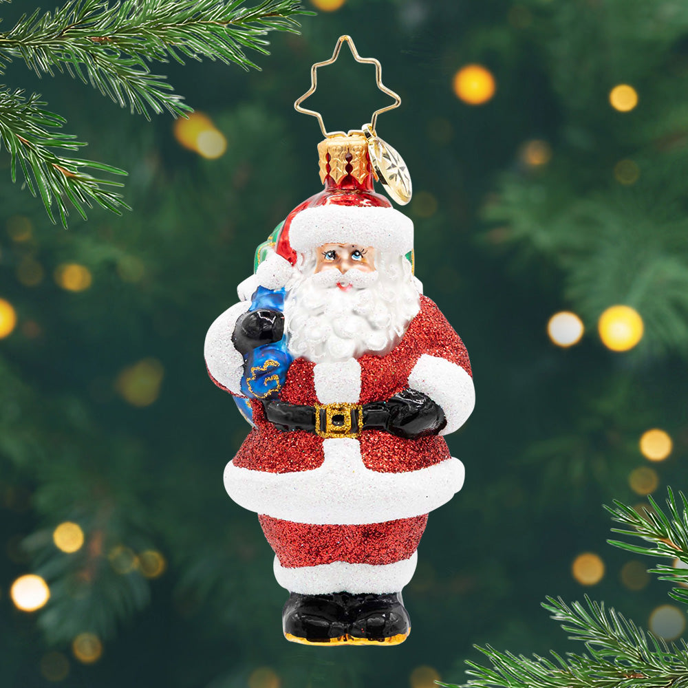 Jolly Old Kris Kringle Gem. Santa ornament in a sparkly red suit and holding a blue bag. View of front