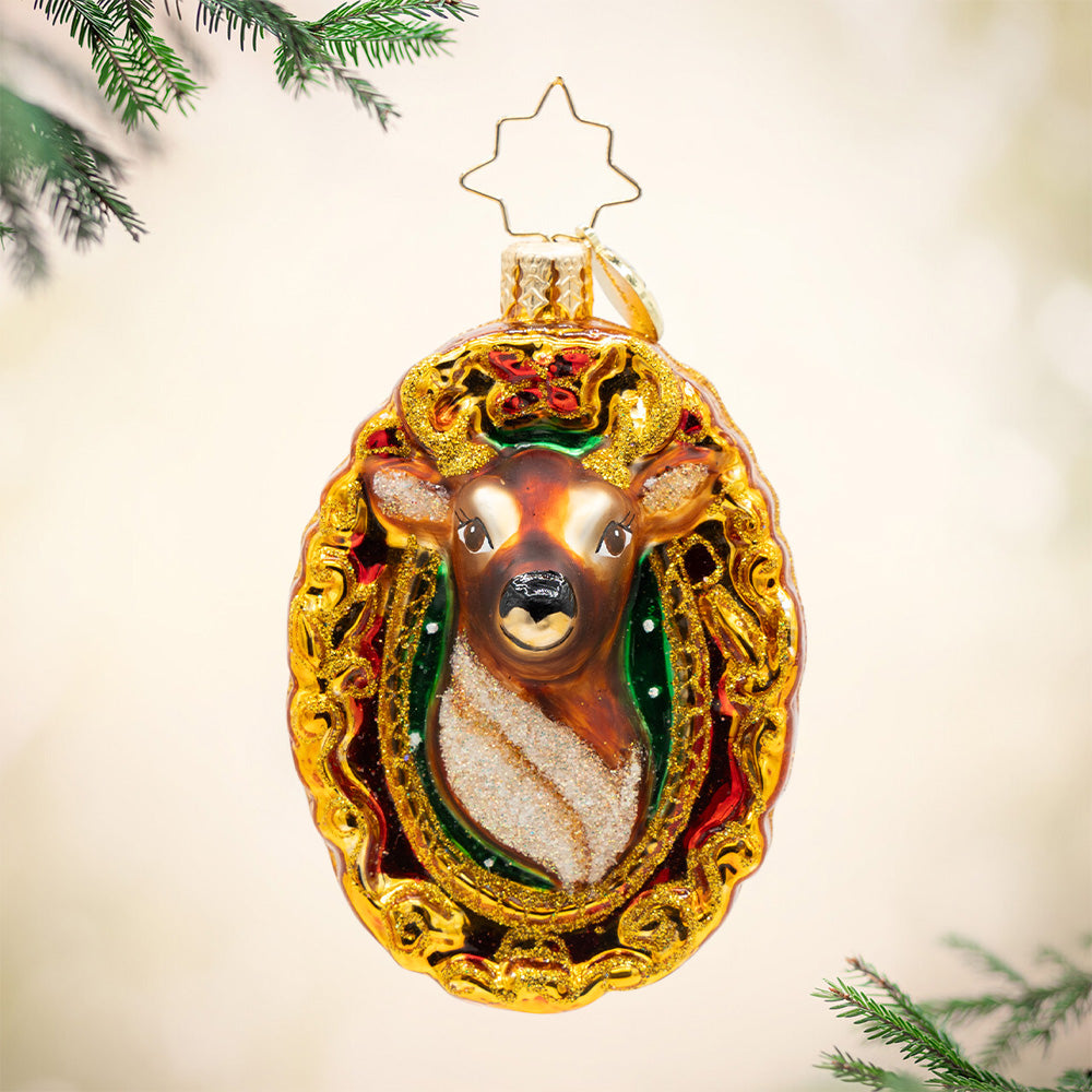 Mantle Majesty Gem. Ornament of a brown reindeer head in a golden detailed frame. View of front