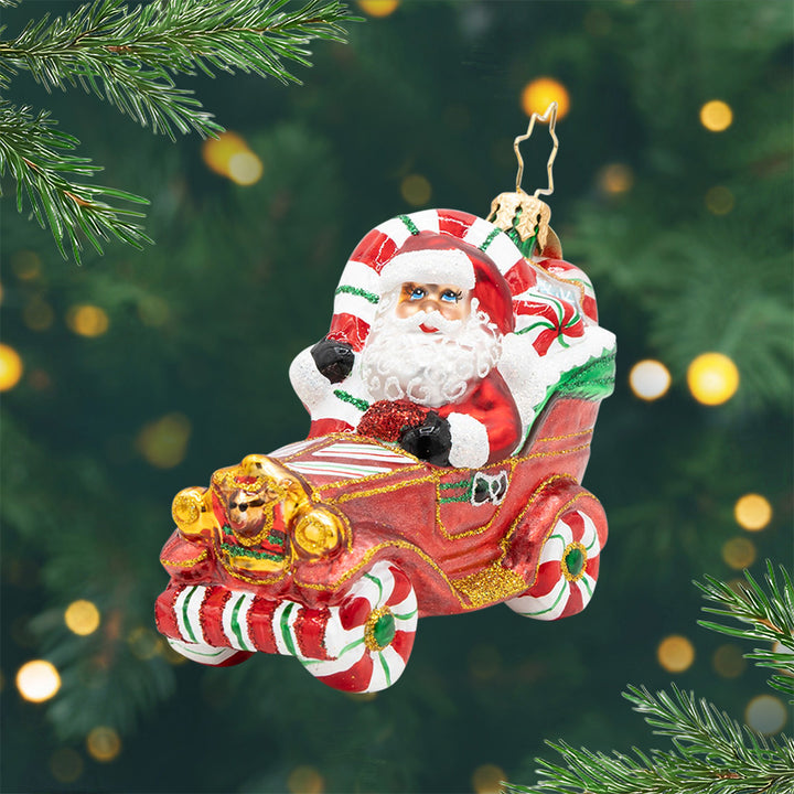 Sweet Ride Cruiser Gem. Ornament of Santa in a red car with peppermint wheels. View of front