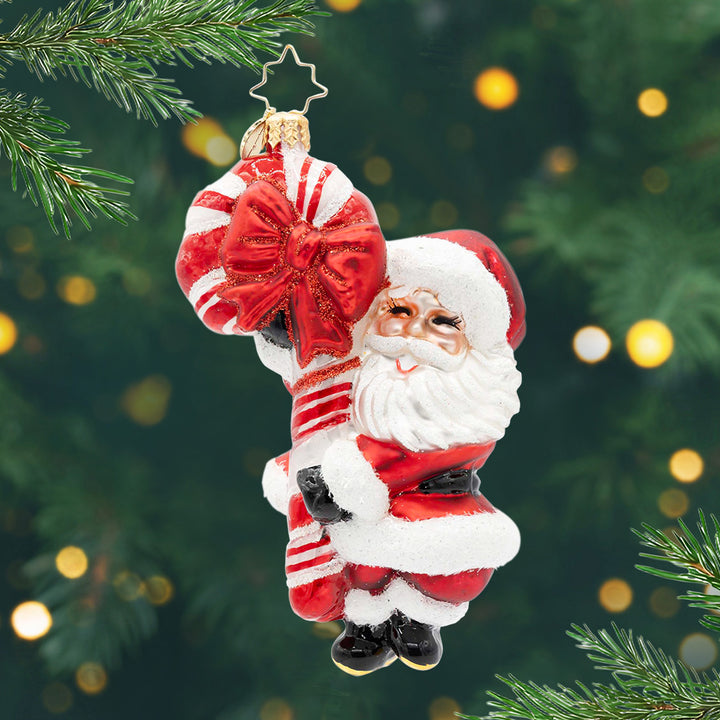 St. Nick's Retro Cheer. Ornament of Santa Holding a giant sparkly candy cane with a red bow. View of front