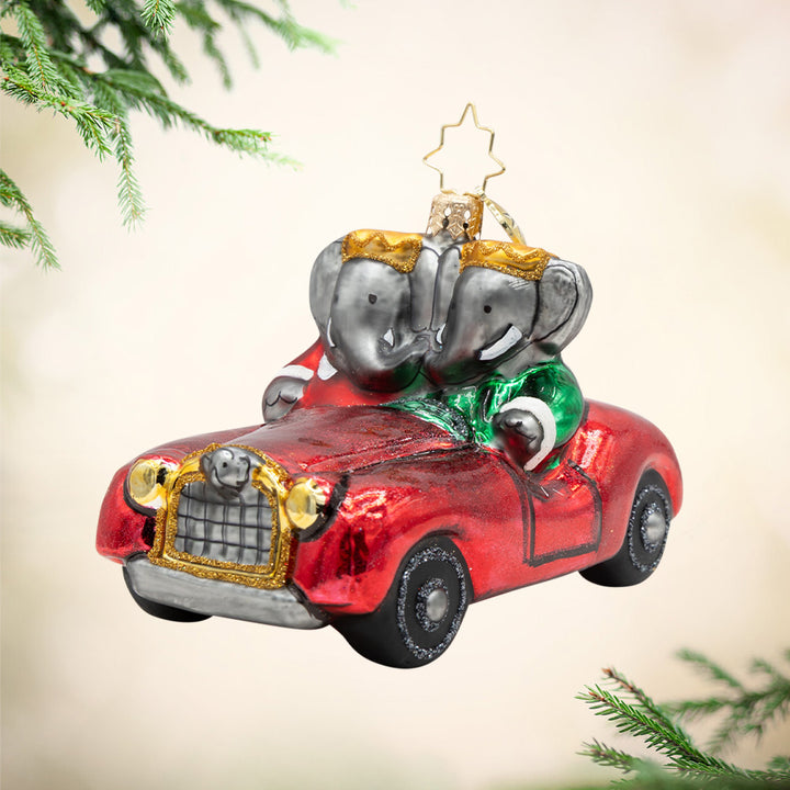 Babar & Celeste's Royal Ride. Ornament of Babar and Queen Celeste cruising in their red convertible, with golden crowns, red and green coats, and trunks entwined. View of front.