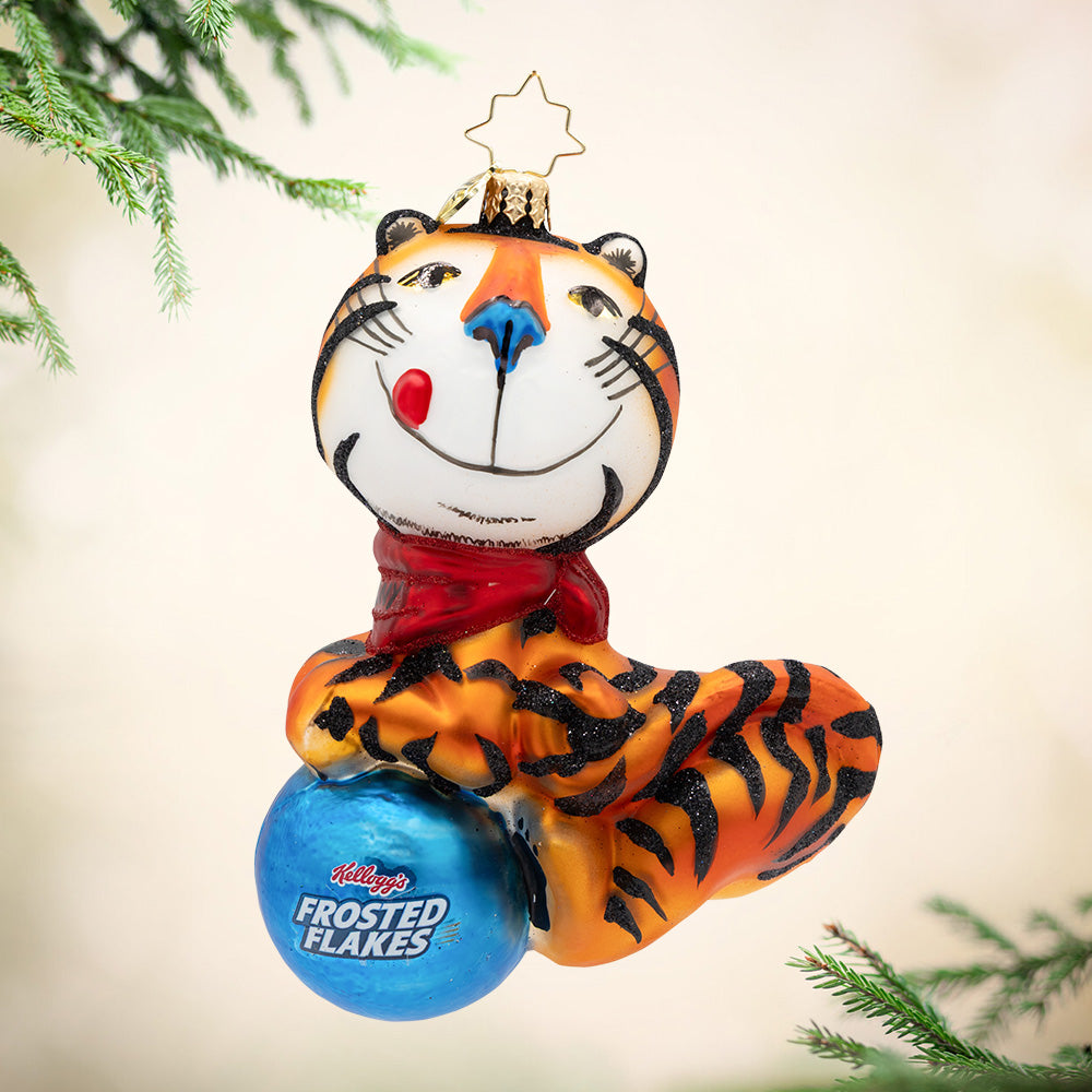 GR-R-REAT Holiday Cheer. A very orange Tony the tiger resting on a blue ornament with Kelloggs logo and the Phrase "Frosted Flakes.