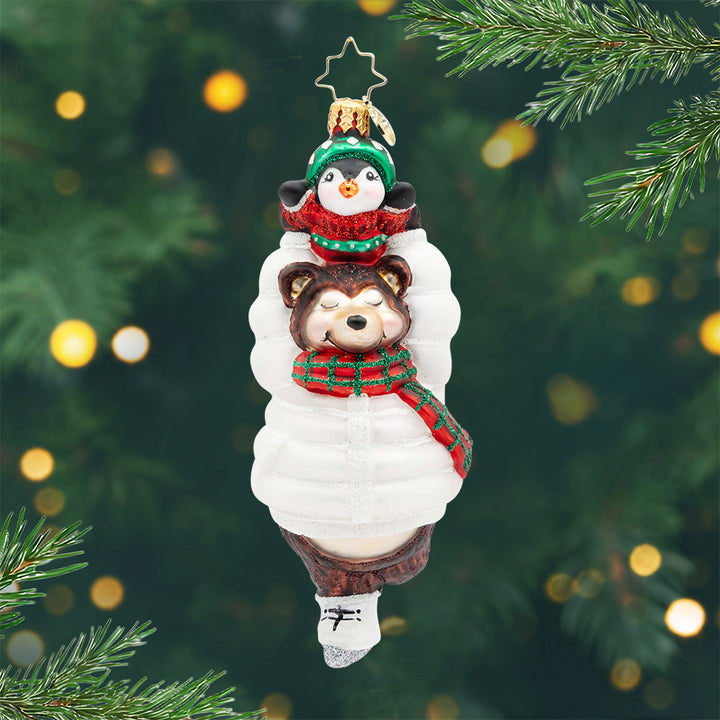 Bearly Skating. A skating bear ornament in a white coat, carrying a little penguin, who is wearing a red sweater, over its head. View of front.