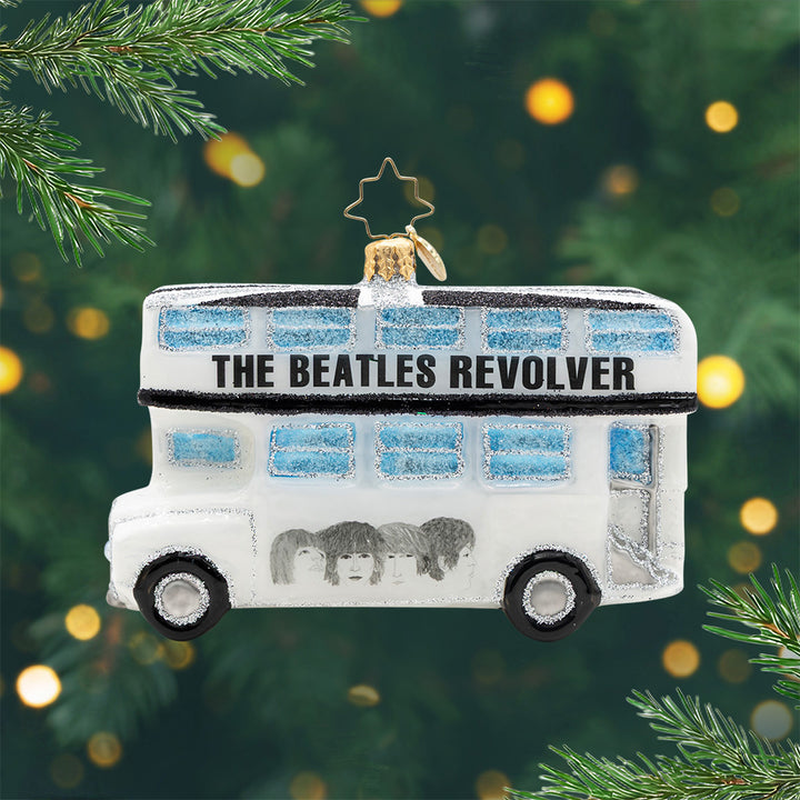 Beatles Revolver Bus. Ornament of a white  and silver bus with blue sparkling windows and the Beatles faces and the spelling of the phrase "The Beatles Revolver. View of front