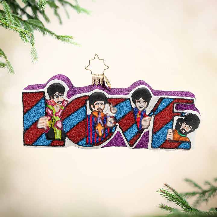 Beatles Love. Ornament of the four members of the Beatles surrounding the word "LOVE" in sparkling stripped pattern with colors of purple, red, and blue. View of front