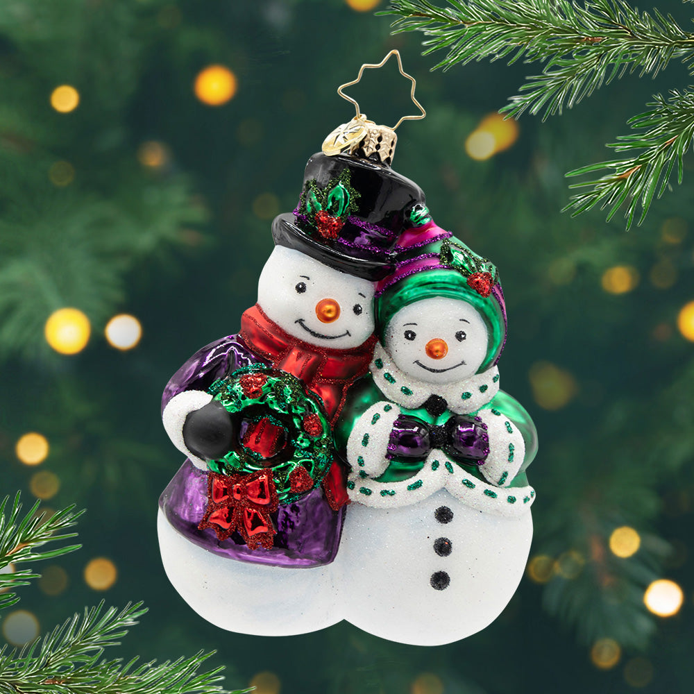 The Snow-Stopper Pair. Snow couple ornament dressed in a purple coat and a green coat. View of front