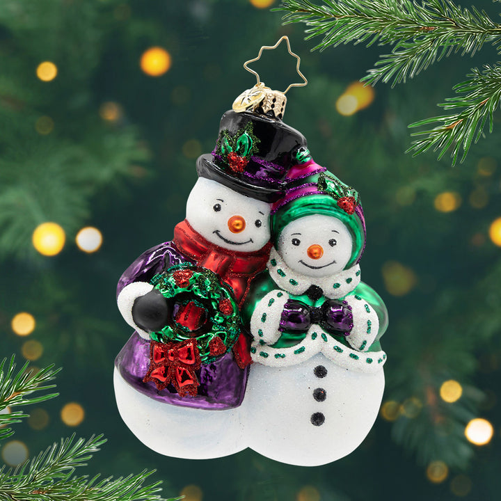 The Snow-Stopper Pair. Snow couple ornament dressed in a purple coat and a green coat. View of front