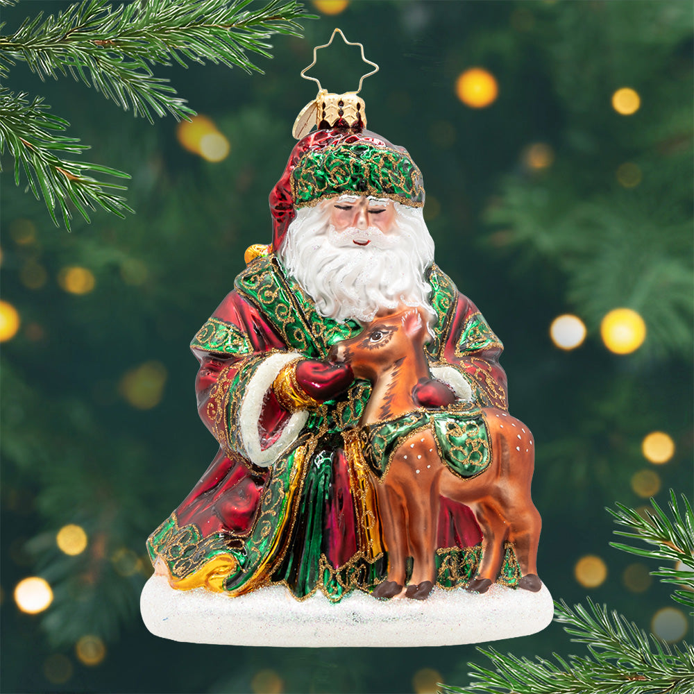 A Woodland Offering. Ornament of Santa feeding a reindeer in a red and green robe with gold detailing. View of front