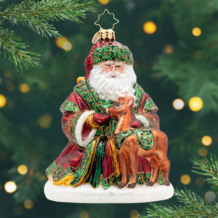 A Woodland Offering. Ornament of Santa feeding a reindeer in a red and green robe with gold detailing. View of front