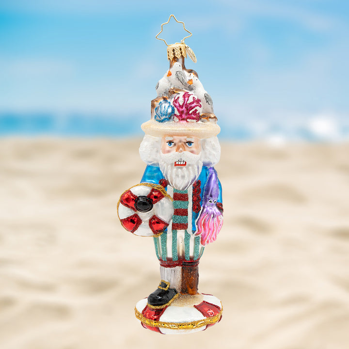 The Nautical Nutcracker. Ornament of Nutcracker dressed in blue with red and green stripes and a hat with seagulls, along with holding a lifesaver and a purple octopus. View of front
