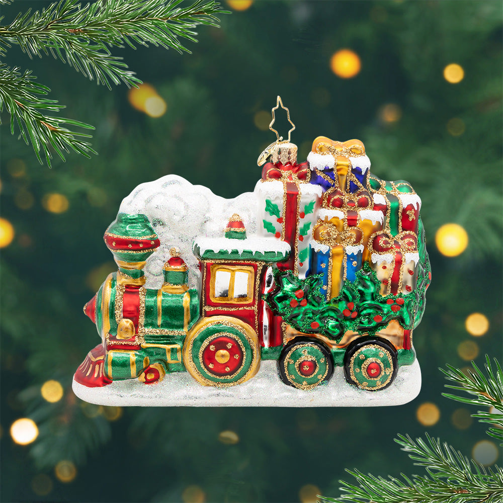 Yuletide Express. Ornament of a train in colors of red, green and good detailing carrying a load of different presents covered in snow. View of front.
