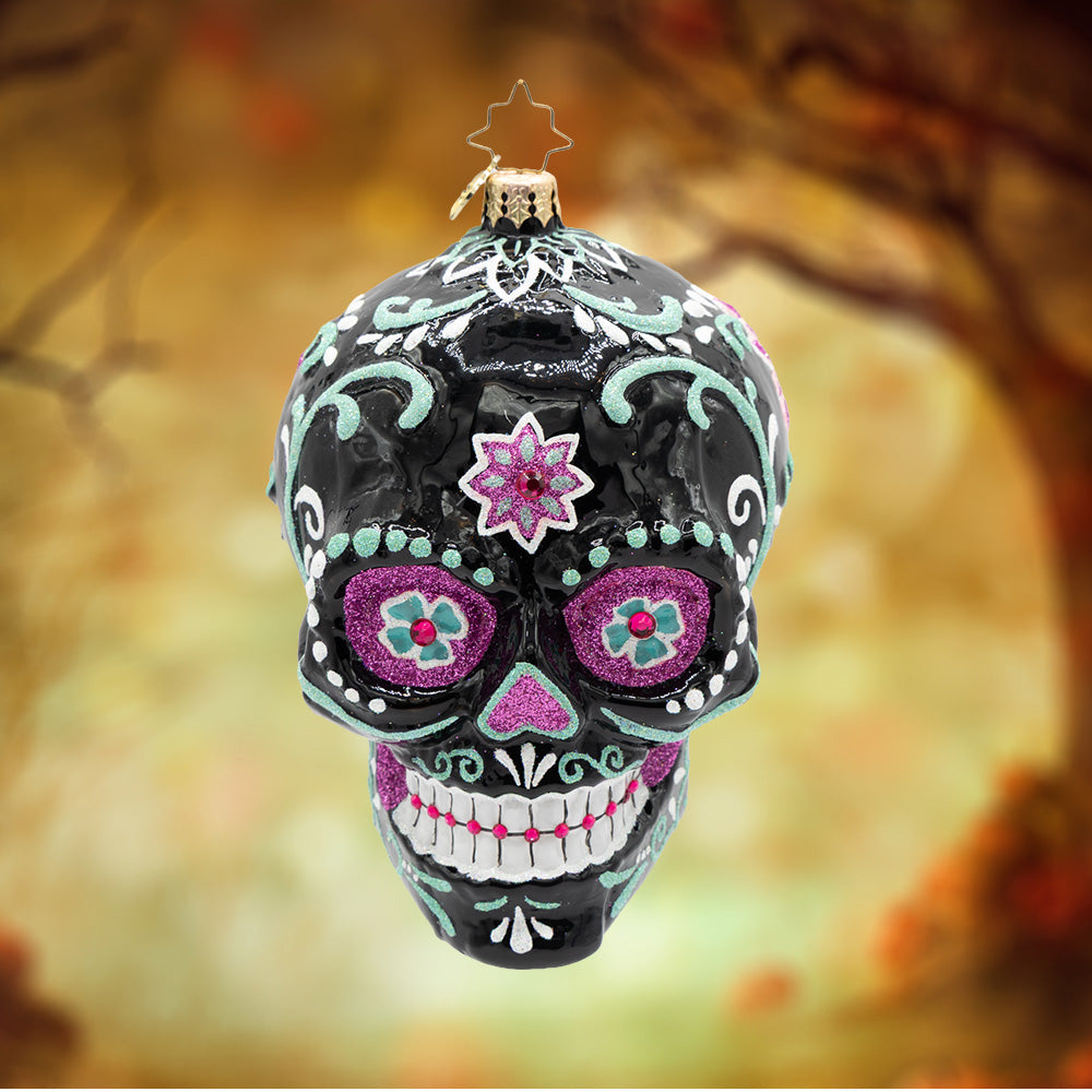 Calavera Rosada. A black skull ornament with teal, white, and purple detailing.