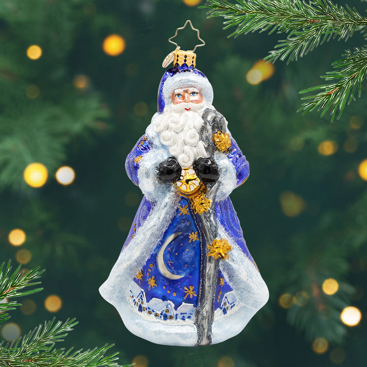Starlight Santa. Ornament of Santa is dressed in midnight blue and trimmed in white with a moonlit village scene in the robe and holding a star-topped staff. View of front
