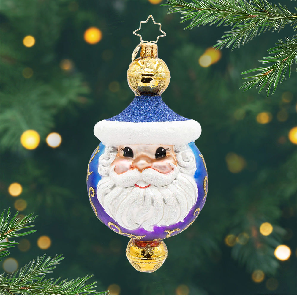 Jingle Top Gent. A round ornament in a blue and purple ombre with Santa's face in the front and a gold bell on top and on the bottom. View of front.