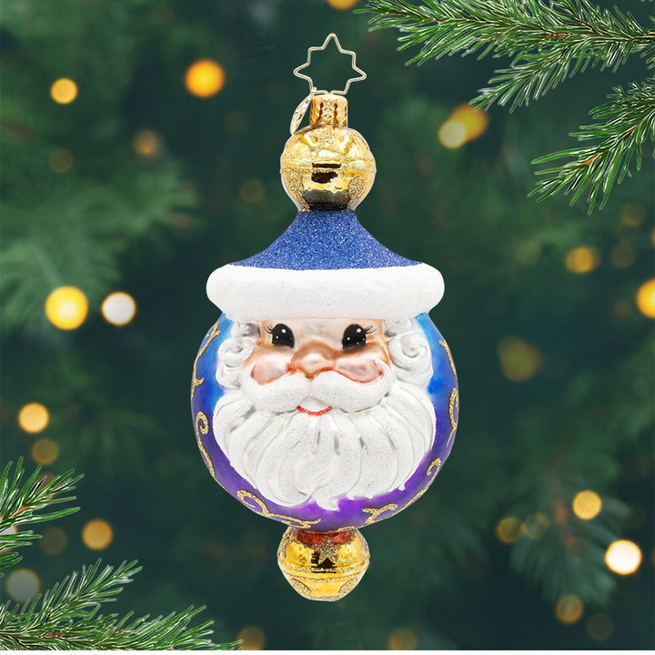 Jingle Top Gent. A round ornament in a blue and purple ombre with Santa's face in the front and a gold bell on top and on the bottom. View of front.