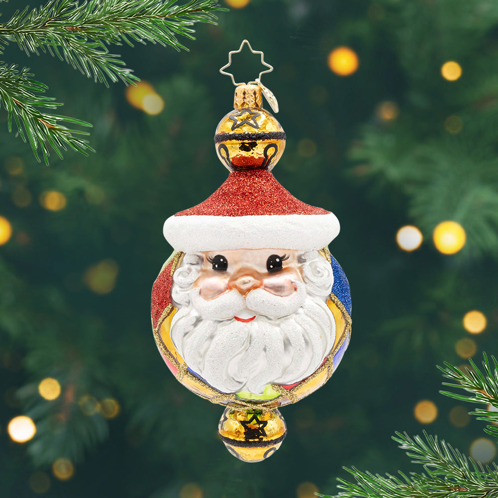 Joyful Jingles. A round ornament of red, blue and gold with Santa's face on the front and a bell at the top and on the bottom. View of front.