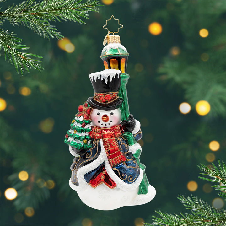 The Holiday Gentlemen. Ornament. A snowman dressed in a blue robe and standing next to a green light post. View of front.