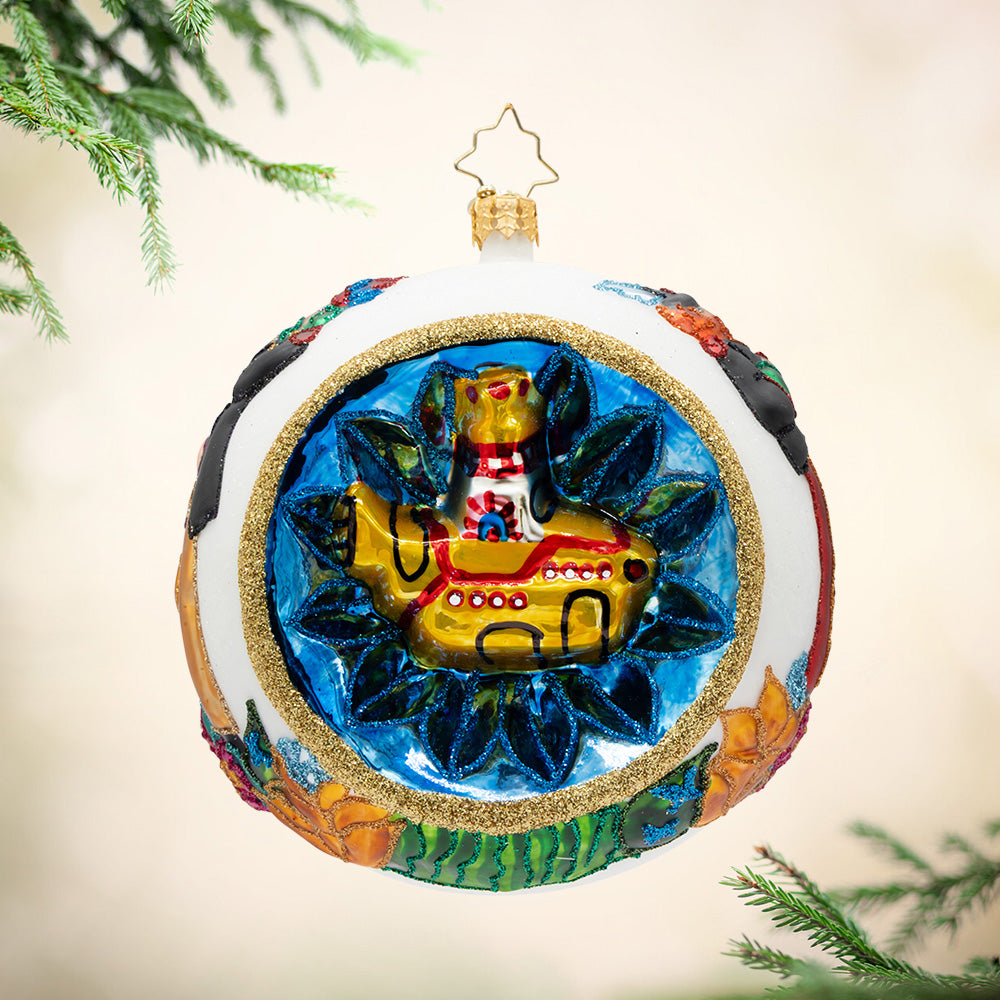 The Fab Four's Festive Voyage. A round white ornament with multiple vibrant colors and a gold submarine surrounded in a circle of blue. View of front.