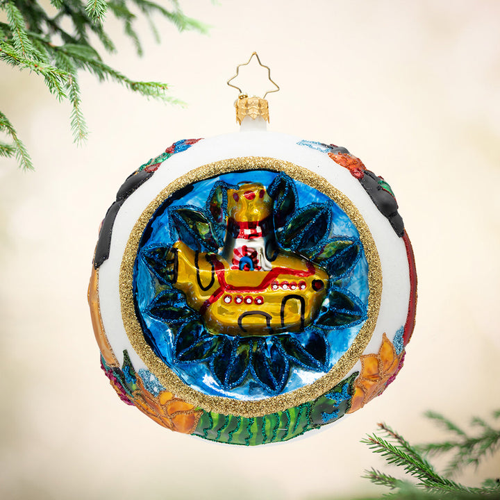 The Fab Four's Festive Voyage. A round white ornament with multiple vibrant colors and a gold submarine surrounded in a circle of blue. View of front.