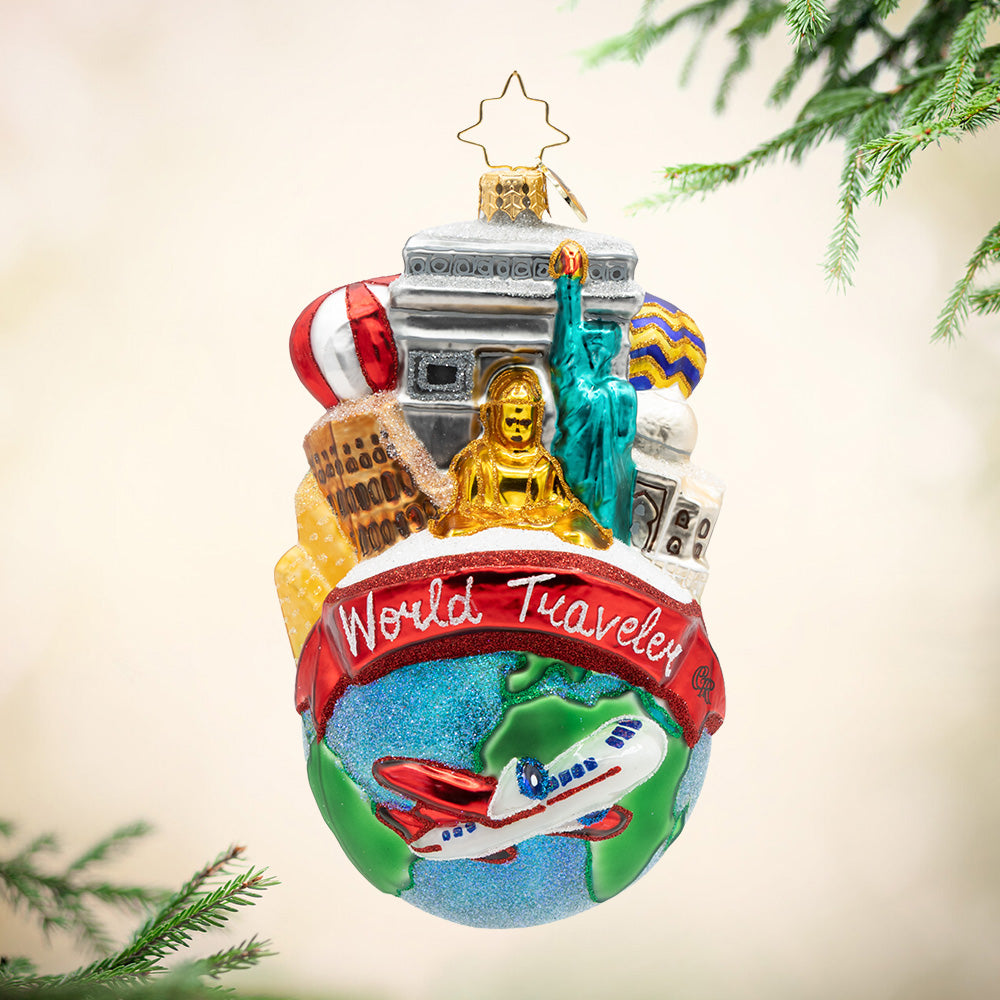 The Merry Explorer. An ornament of the earth with the phrase "Would Traveler" and a plane beneath it and different destinations on top. View of front