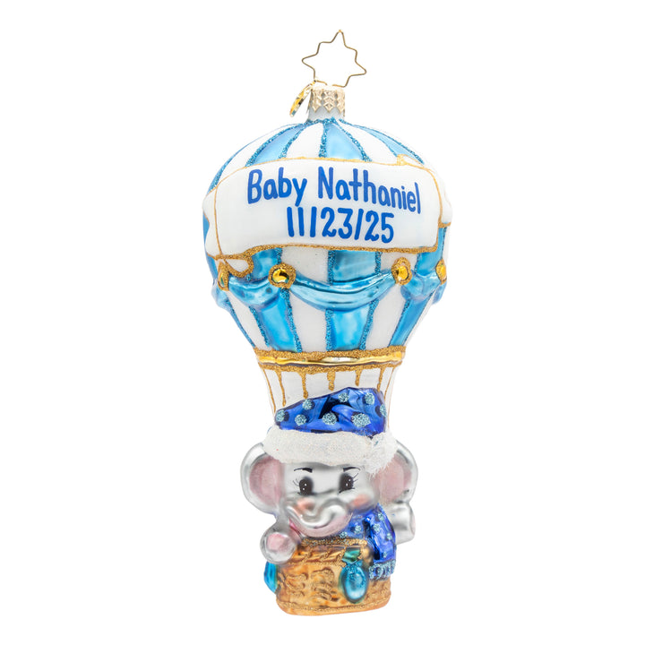 A personalized baby elephant ornament shaped like an elephant riding a hot air balloon. The ornament features the name 'Baby Nathaniel' and a birth date '11/23/25' printed on the balloon's banner.