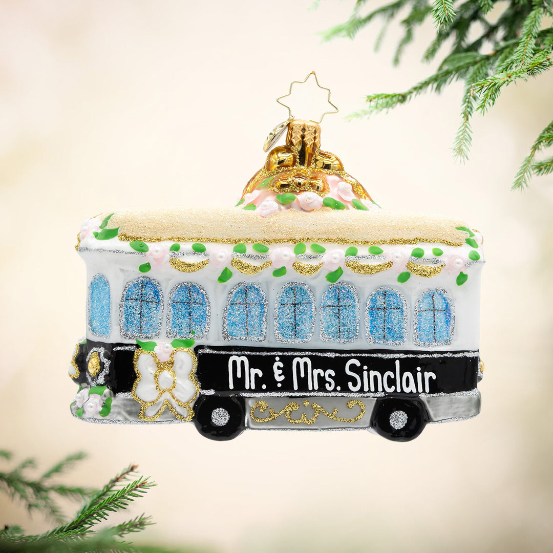 Decorative tram ornament with 'Mr. & Mrs. Sinclair' text, hanging on a tree.