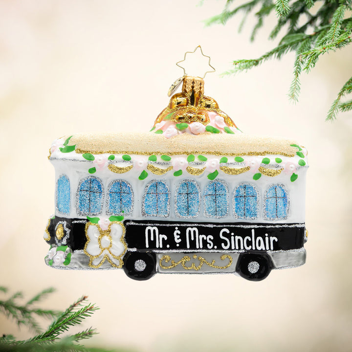 Decorative tram ornament with 'Mr. & Mrs. Sinclair' text, hanging on a tree.