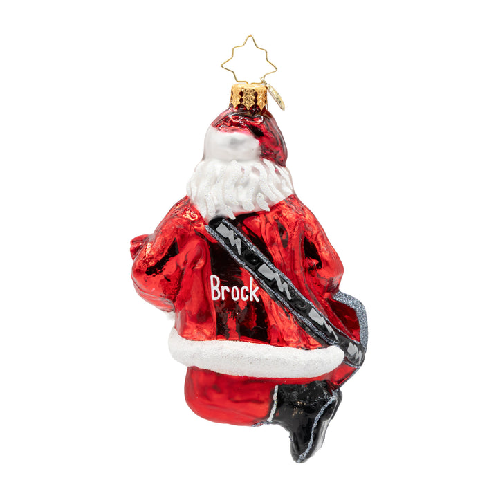 A personalized Christmas glass ornament depicting Santa Claus from the back, wearing a red suit with white fur trim and a black strap across his back. The name 'Brock' is printed in white on the back of the suit.