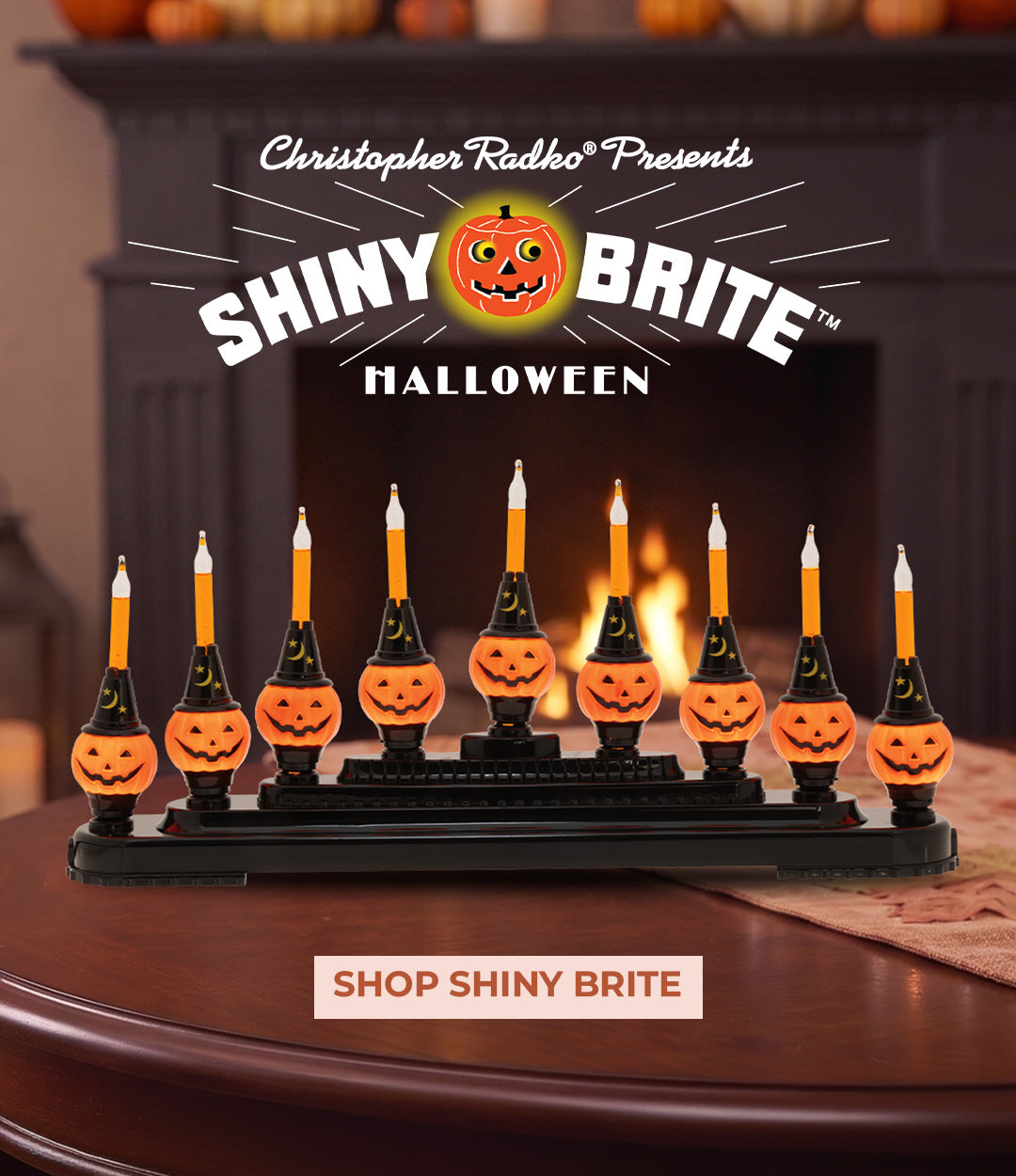A row of jack-o'-lantern-shaped candle lights displayed on a mantel candelabra in front of a fireplace.