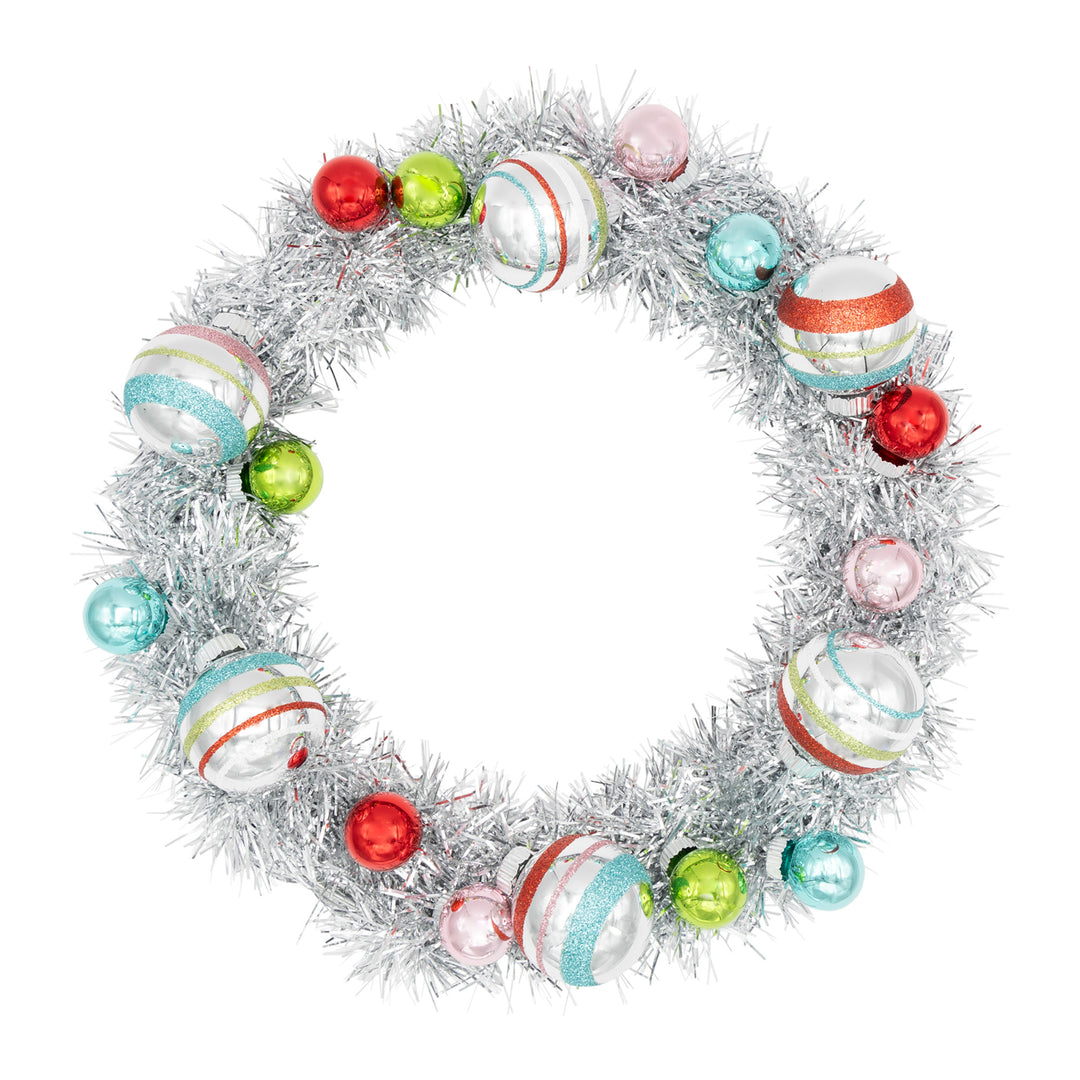 FESTIVE FETE SILVER TINSEL WREATH WITH 1" AND 1.75" ROUNDS. Silver tinsel wreath with small ornaments in colors of red, green, teal, and pink and some bigger silver ornaments with red, green, teal, and pink stripes.