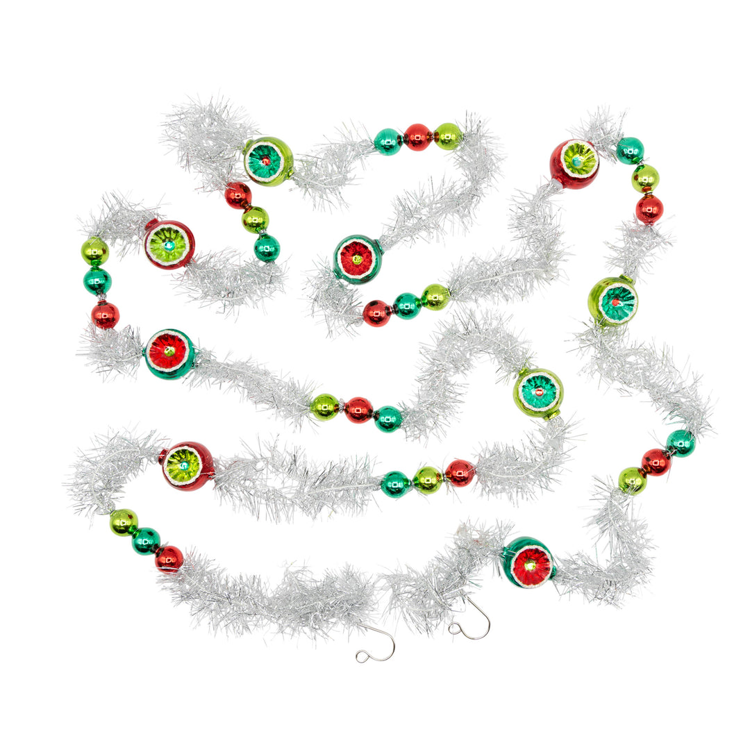 HOLIDAY SPLENDOR 1 COUNT 7' TINSEL GARLAND. Silver tinsel garland with little ornaments ranging in colors of red, dark and light green.