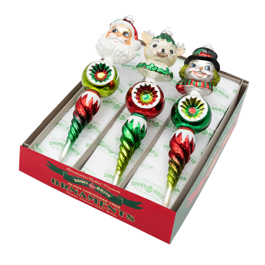 HOLIDAY SPLENDOR 3 COUNT 10.5" FIGURE ROUNDS. Three icicle ornaments with colored in red and green ombré, along with each having a different figure's head of either Santa, a snowman, or a reindeer.