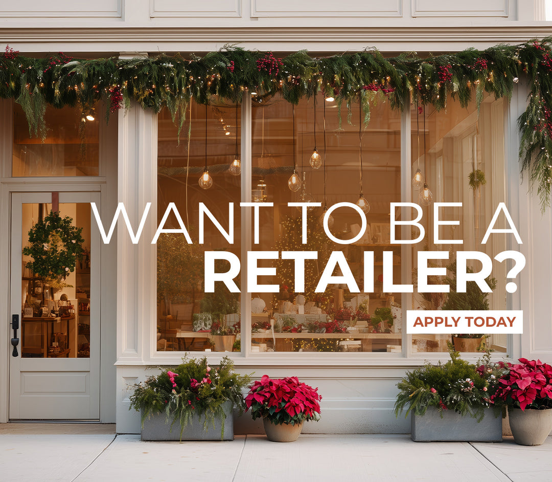A festively decorated storefront window with holiday garland, wreath, and poinsettias, promoting retailer applications with an 'Apply Today' button.
