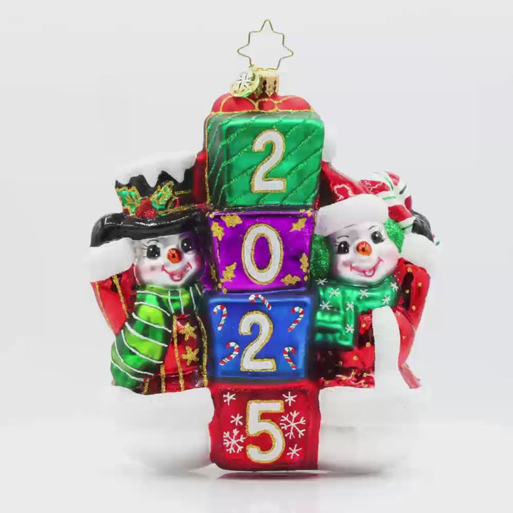 2025 Snowy Stackers ornament. These two snowmen are stacking up presents like building blocks. The gifts are dated with "2025." Video.