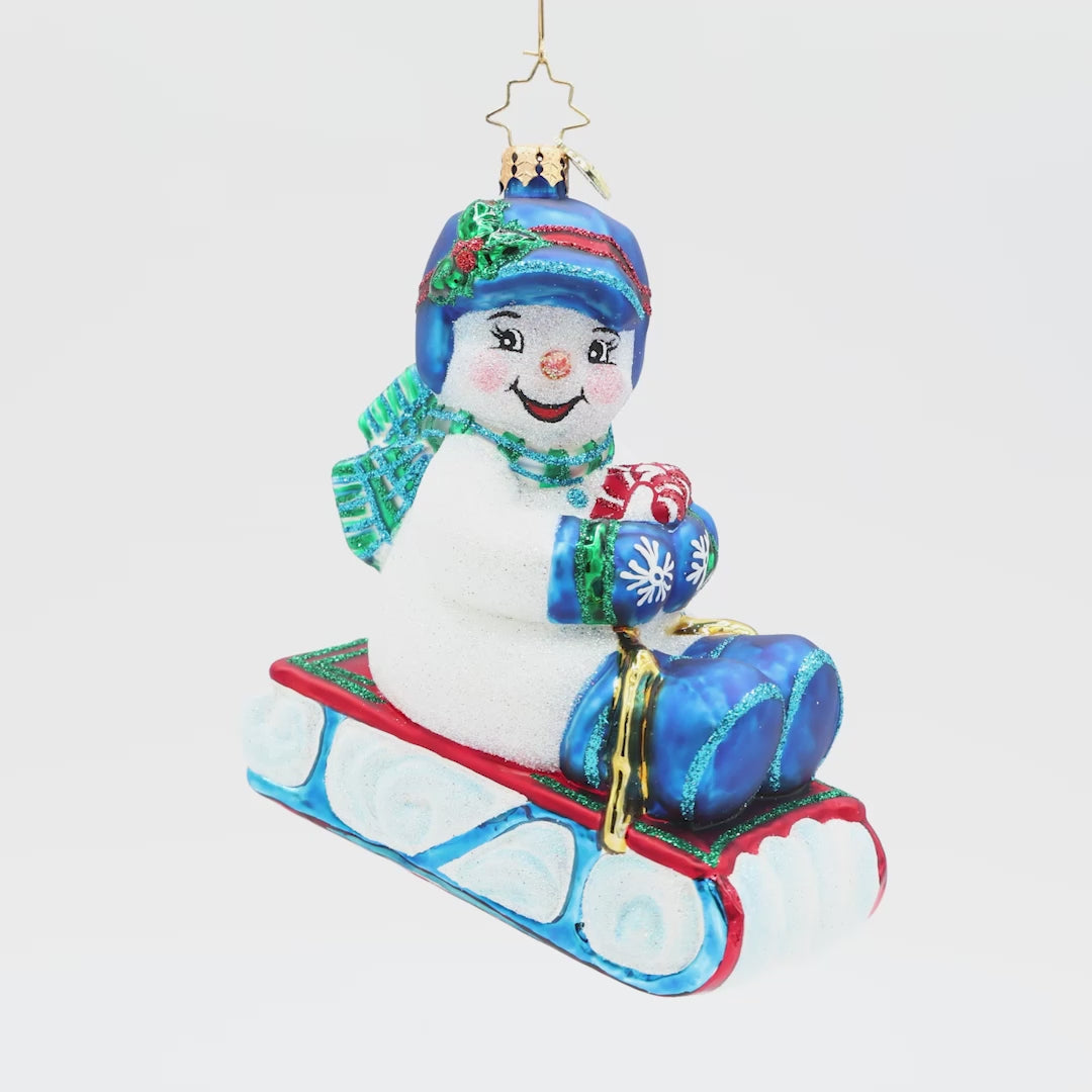 Decorative snowman ornament with a blue hat and scarf holding candy canes in their arms on a white background