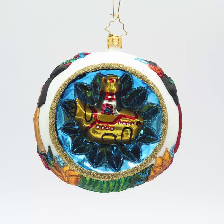 Front view of a round white ornament with multiple vibrant colors and a gold submarine surrounded in a circle of blue. 