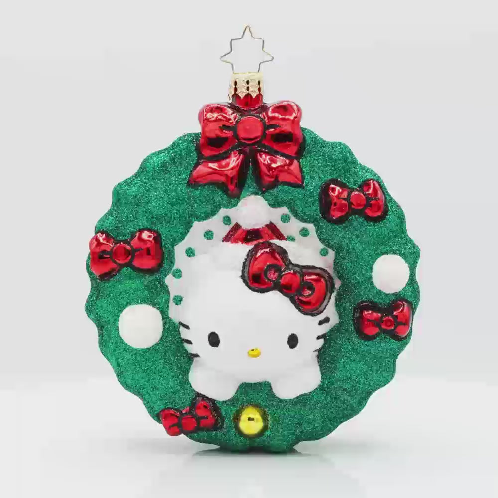 Hello Kitty's Holiday Wreath ornament. Hello Kitty wears her signature red bow nestled in a festive wreath adorned with red bows, holly, and sparkly accents. Video.