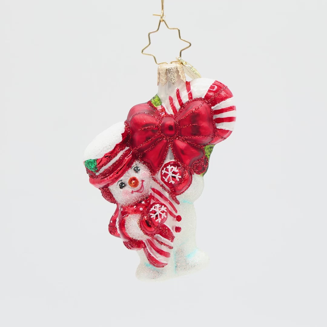 Decorative ornament of a snowman with a large red bow and candy cane, on a white background.
