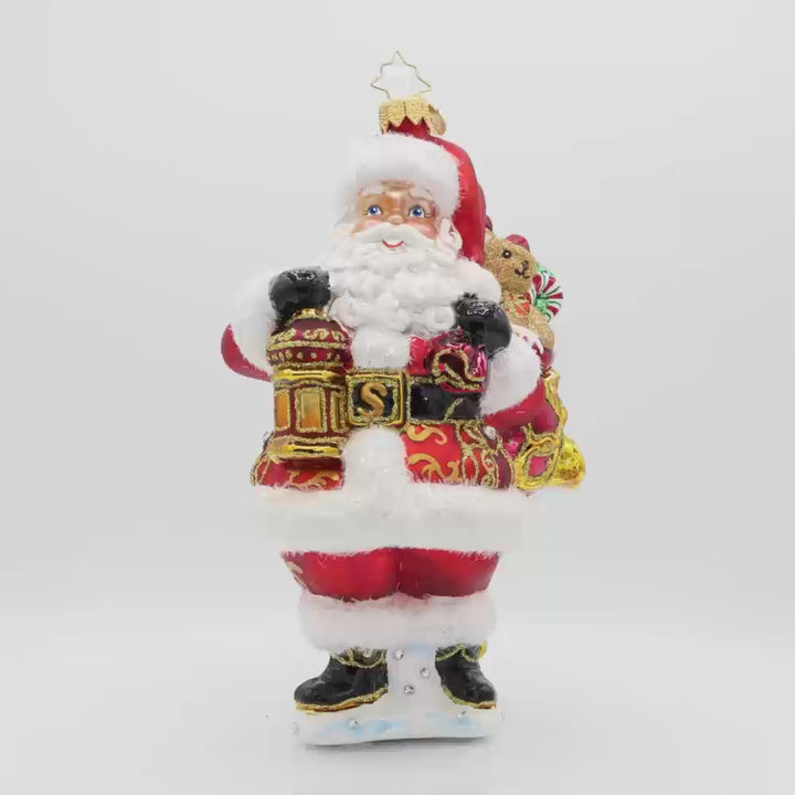 A Clause to Celebrate ornament. With his festive lantern, sparkling eyes, and a cuddly teddy bear by his side. He's dressed in his traditional red suit and hat. Video.