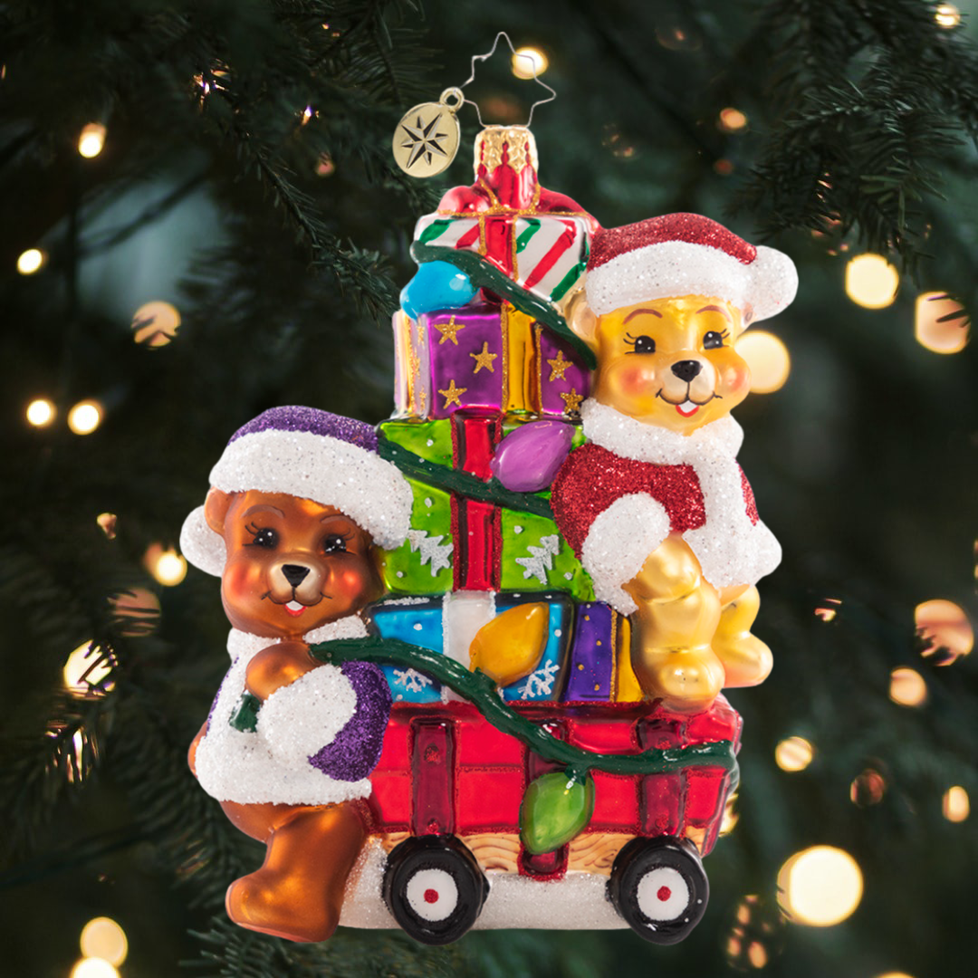 Ornament Description - Toting Treasure Teddies: Wishing you a very bear-y Christmas! These precious plushies are riding in style on their little red wagon piled high with toys and Christmas joy!