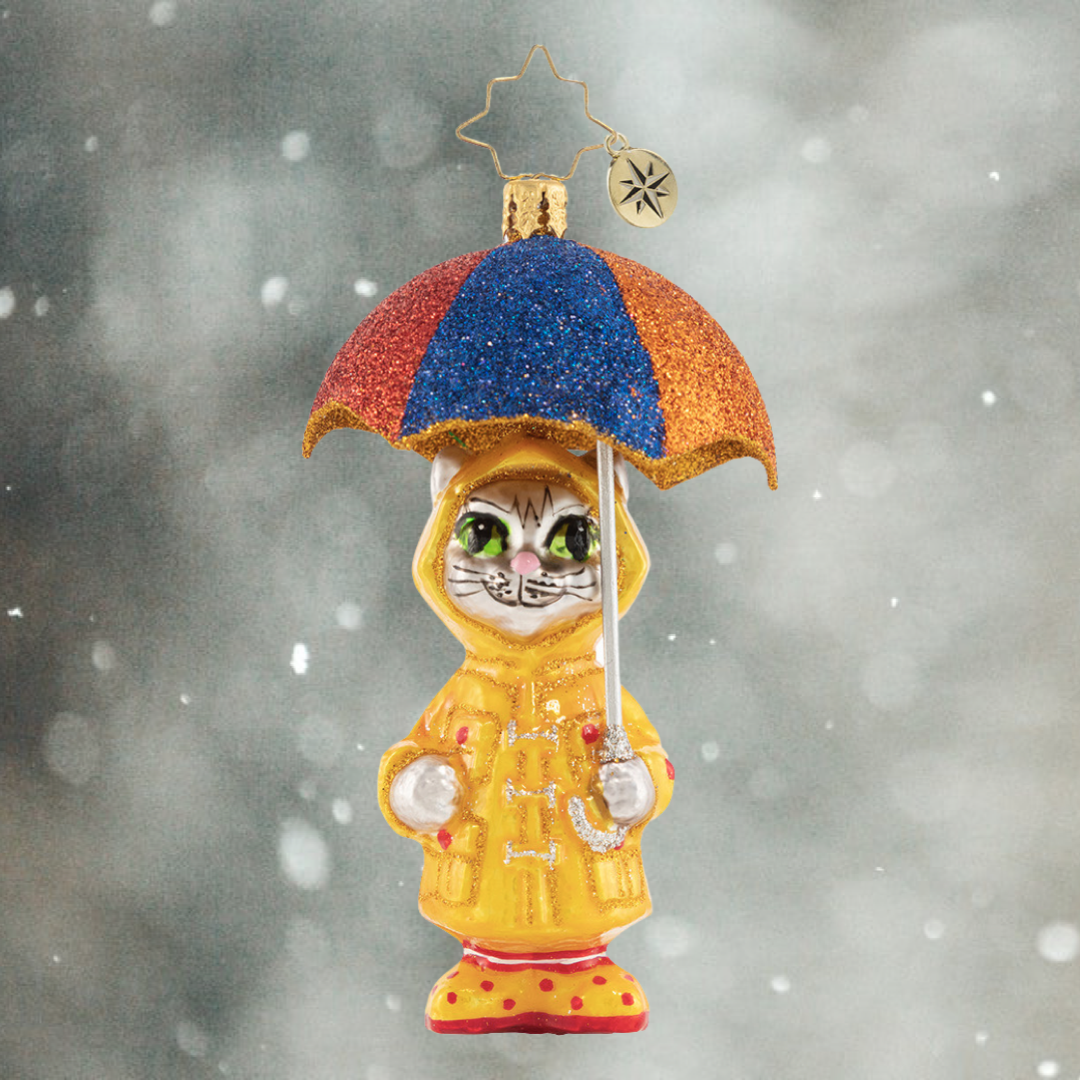 Ornament Description - It's Raining Cats! Gem: This itty bitty kitty has the right idea for staying dry when it is really coming down. Got to love that drizzly-day fashion!