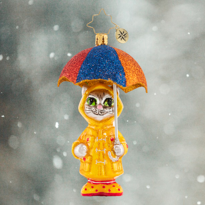 Ornament Description - It's Raining Cats! Gem: This itty bitty kitty has the right idea for staying dry when it is really coming down. Got to love that drizzly-day fashion!