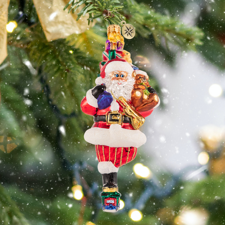 Ornament Description - Traversing By Toy Truck: Does that thing have an engine? Always at the forefront of magical Christmas transportation trends, Santa tries something new; he gives this option a 7 for style, a 6 for speed, and a 10 for fun!