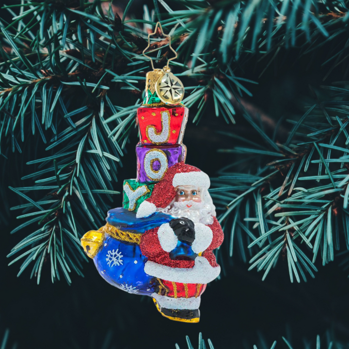Ornament Description - Joyous Saint Nick Gem: Santa's his name, and JOY is his game! Everyone's favorite elf carries a sack piled high with surprises, primed to spread Christmas cheer to one and all.