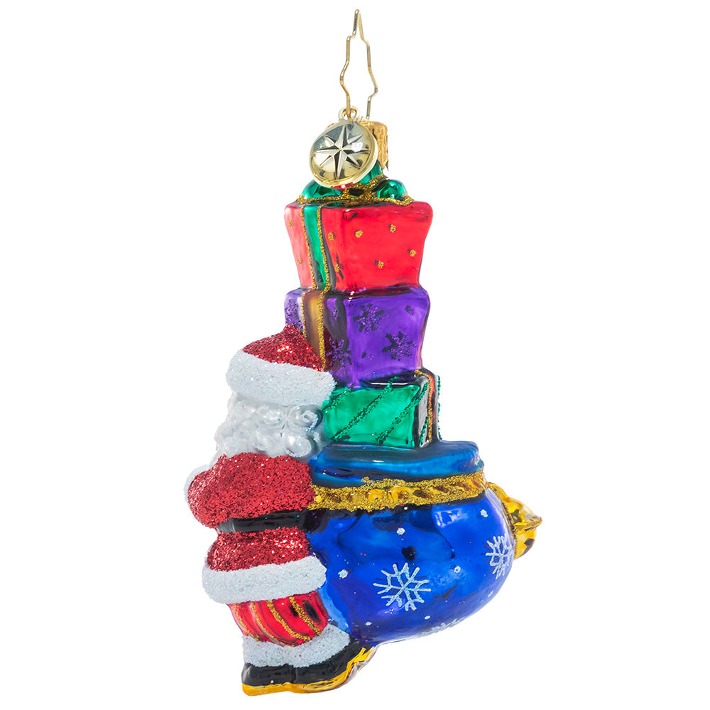 Back - Ornament Description - Joyous Saint Nick Gem: Santa's his name, and JOY is his game! Everyone's favorite elf carries a sack piled high with surprises, primed to spread Christmas cheer to one and all.
