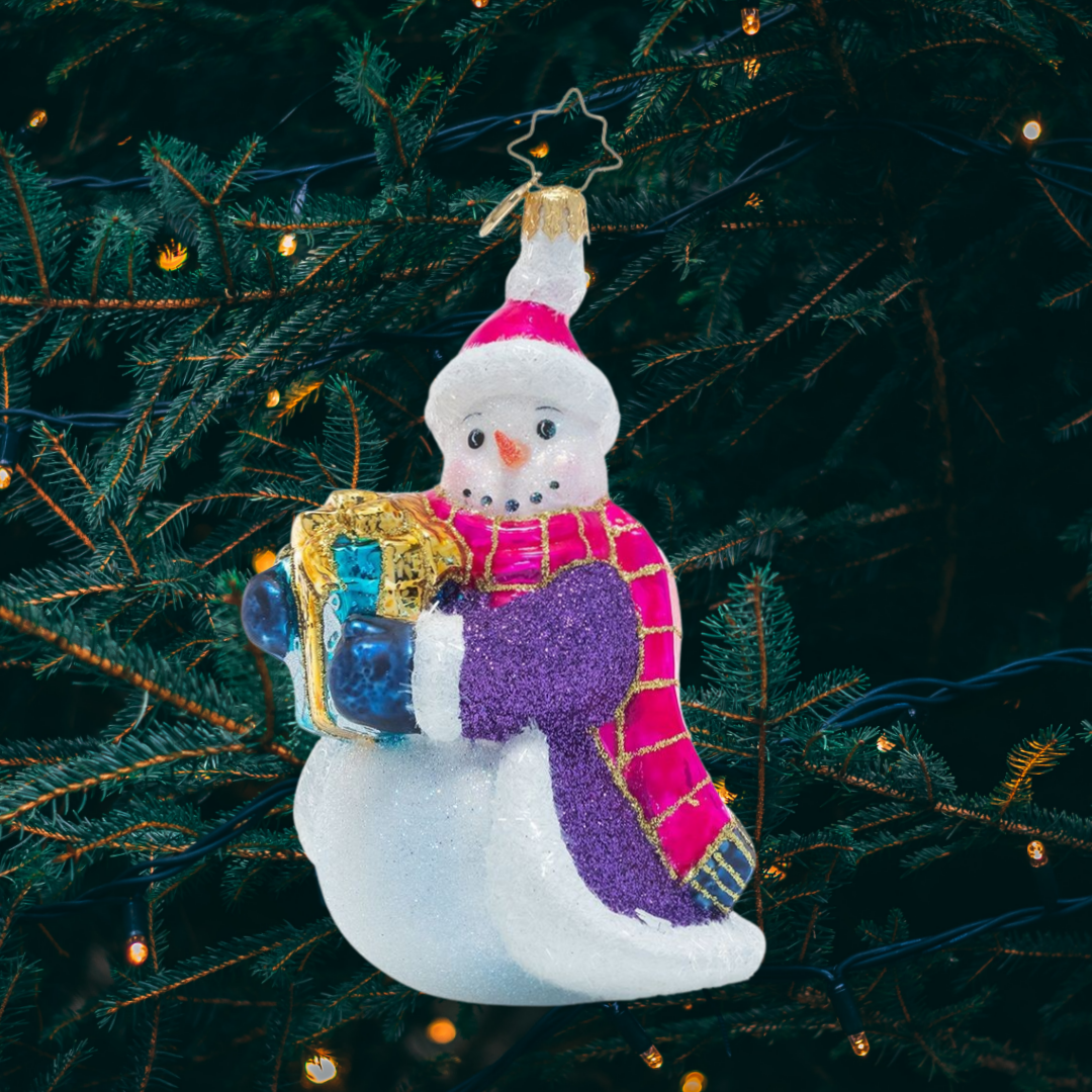 Ornament Description - Smilin' And Stylin': This cheerful snowman has chosen some fabulous finery to guard him against the chill of winter as he travels to share a gift with a friend. He knows no ensemble is complete without a sparkly cloak and vibrant accessories. This snowman is certainly celebrating the holidays with his own unique flair!