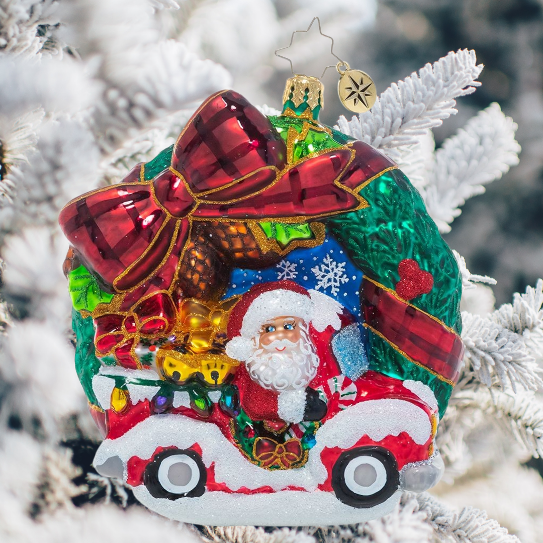 Ornament Description - Rustic Christmas Wreath: A festive tartan bow is the perfect accent for this classic Christmas wreath ornament that features swirling snowflakes, bright holly berries and even the big man himself, Santa Claus! He's speeding through in his Christmas pickup with a truckload of last-minute deliveries.