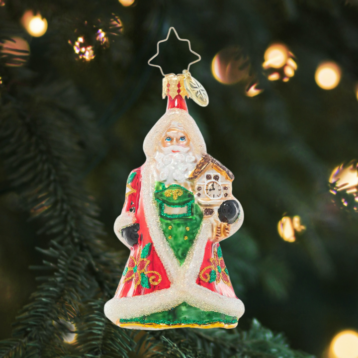 Ornament Description - Punctual In Poinsettias Gem: Tick-tock, check the clock, what time is it? Christmastime is almost here! This festive and floral-clad Santa holds a cuckoo clock to remind us that Christmas is just around the corner.
