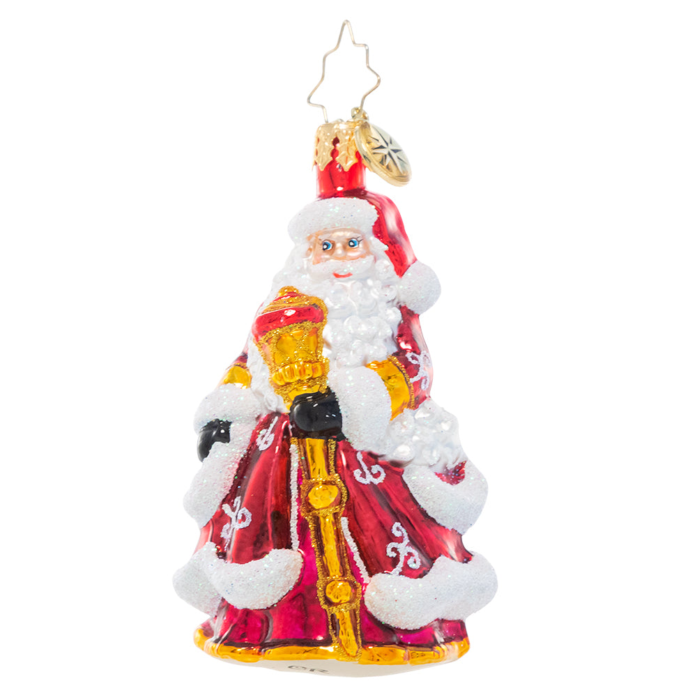 Ornament Description - An En-deer-ing St. Nick Gem: Santa Claus looks extra festive in his ruby red robes decorated with glittering white flourishes. He carries a gleaming golden staff to help light his way through the cold winter's night.