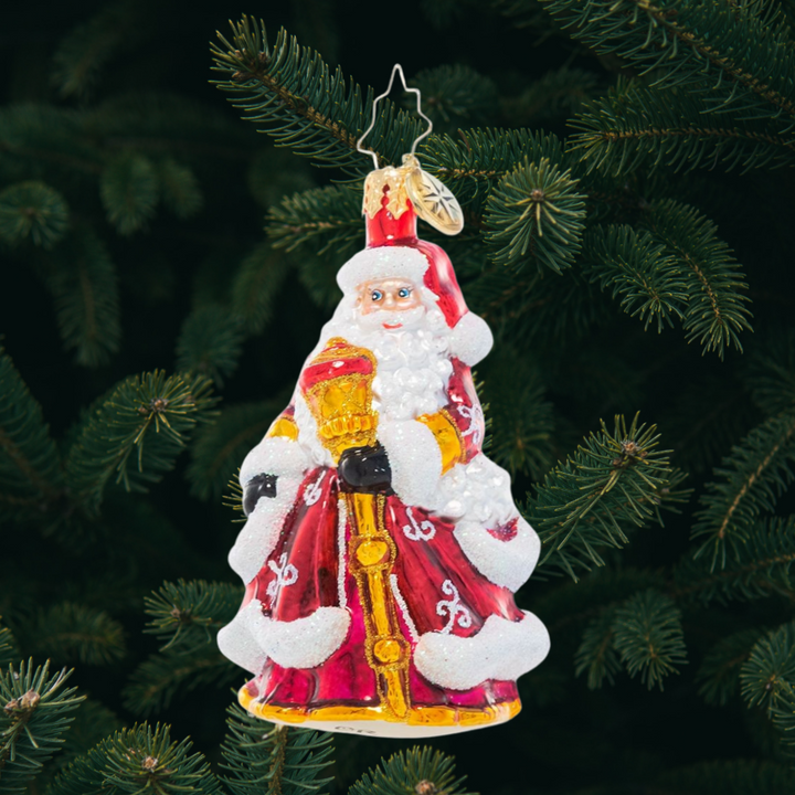 Ornament Description - An En-deer-ing St. Nick Gem: Santa Claus looks extra festive in his ruby red robes decorated with glittering white flourishes. He carries a gleaming golden staff to help light his way through the cold winter's night.